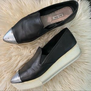 MIU MIU Black leather slip on sneakers/flats accented by silver, metal cap toe